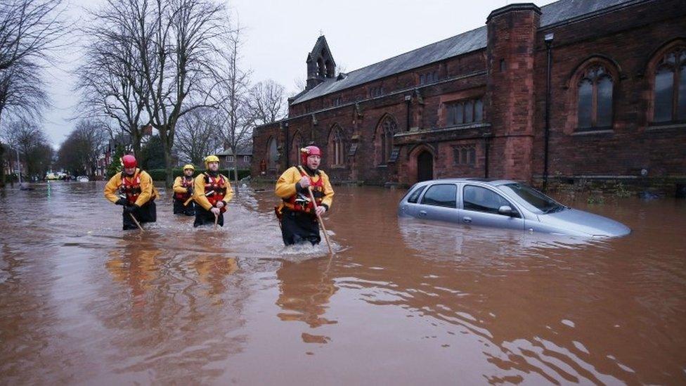 Emergency workers walk through floodwater on Warwick Road in Carlisle