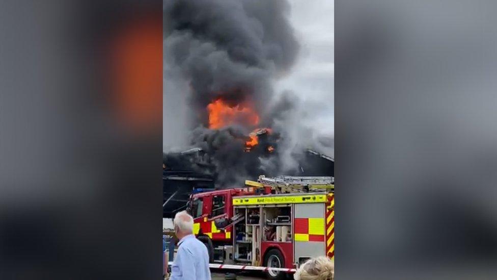 A fire engine dealing with a commercial fire in a black wooden building