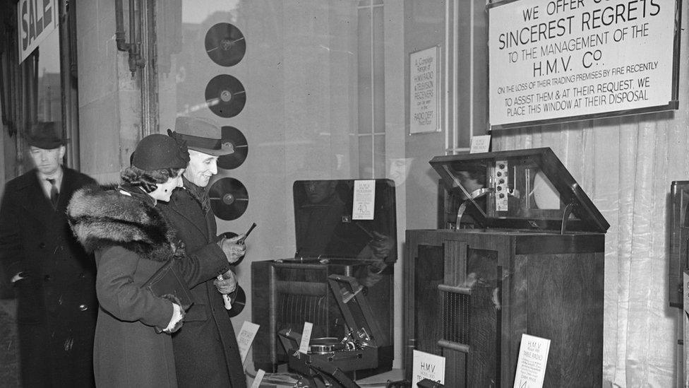 A couple looking at radios in the window of HMV in 1937