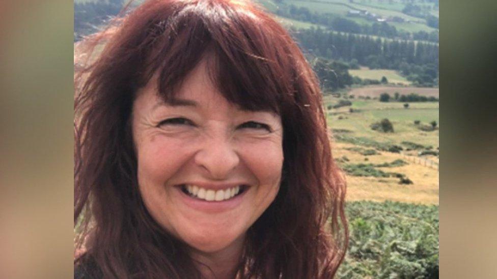 Jo Twist smiles in front of a countryside background