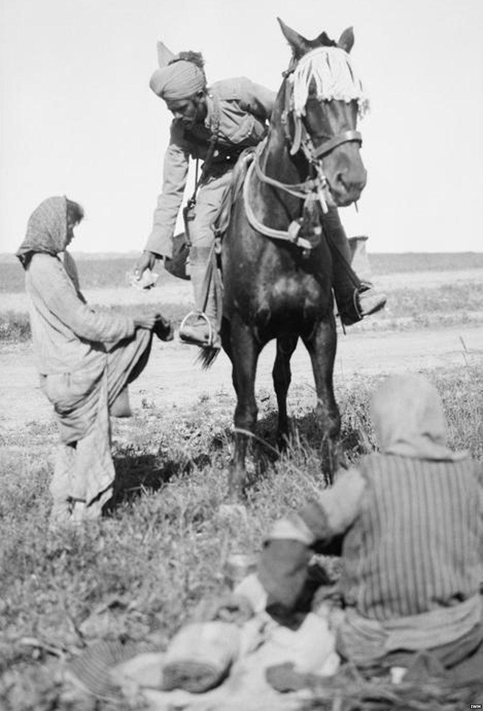 Indian cavalryman hands rations to starving Christian girls