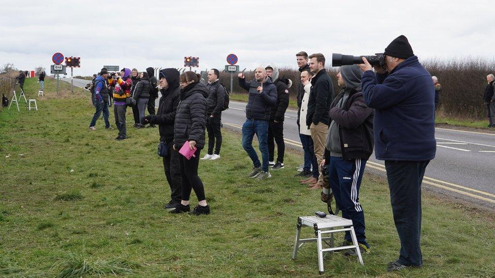 A group of people standing near the fence