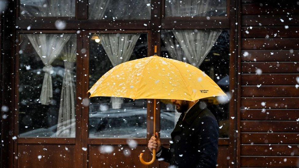 A man walks along a street during a heavy snowfall in Pristina on April 20, 2022