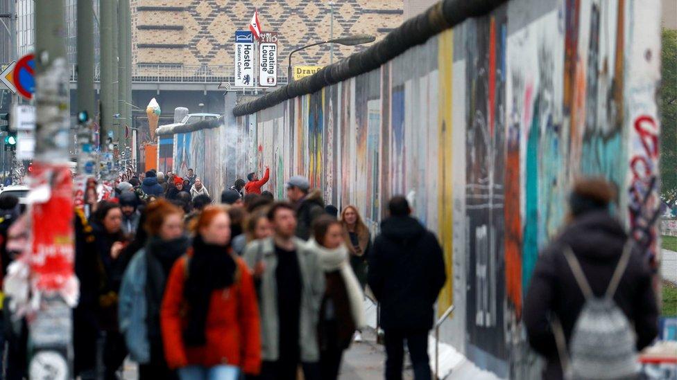 Tourists walk in front of sections at the East Side Gallery, the largest remaining part of the former Berlin Wall, as Germany marks the 28th anniversary of the fall of the wall in Berlin, Germany, November 9, 2017