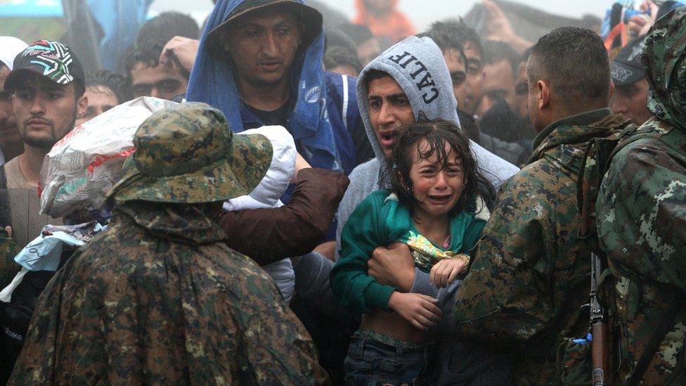 Migrants and refugees wait in the rain to cross the Greek-Macedonian border near the village of Idomeni, in northern Greece on 10 September 2015