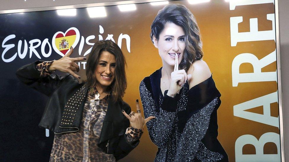 Singer Barei poses in front of a her Eurovision poster