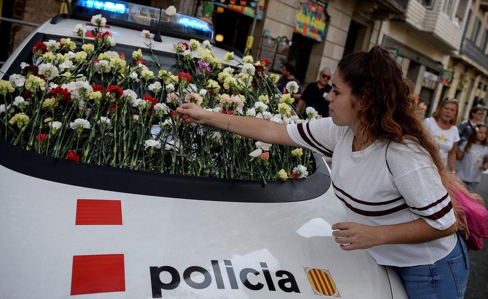 A woman displays a flower on the windshield of a vehicle of Catalan police, known as Mossos d'Esquadra during a pro-referendum rally in Barcelona on September 24, 2017.