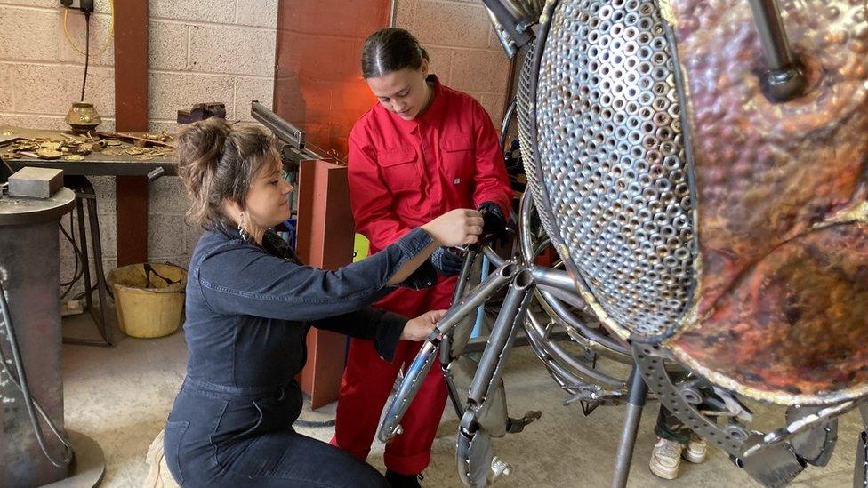 Woman and girl working on parts of the bee