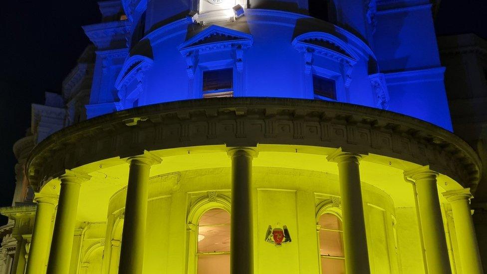 Government buildings lit up in blue and yellow