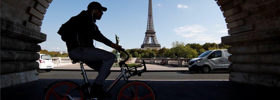 A commuter rides a bike-sharing service mobike bicycle at the Pont de Bir-Hakeim bridge near the Eiffel Tower