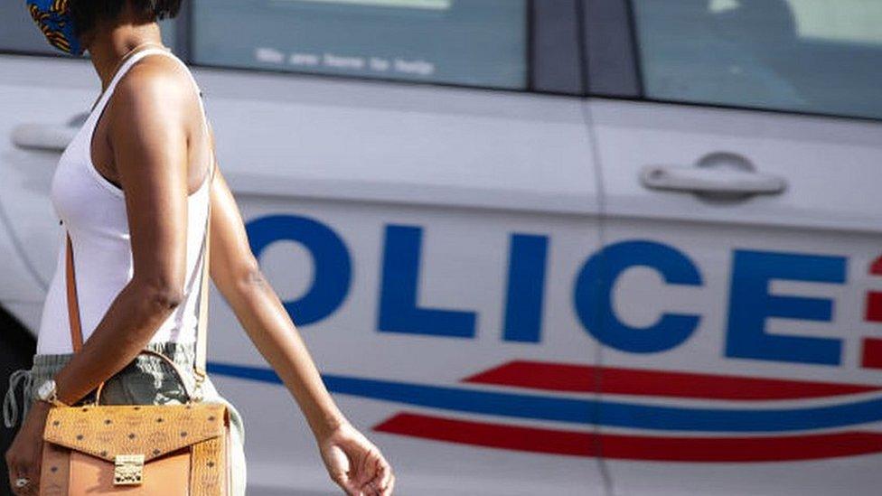 Black woman walks past a police car in Washington DC. May 2020