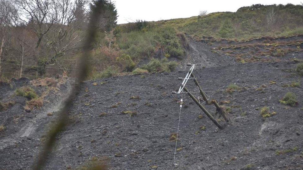 A telegraph pole on its side in a landslide