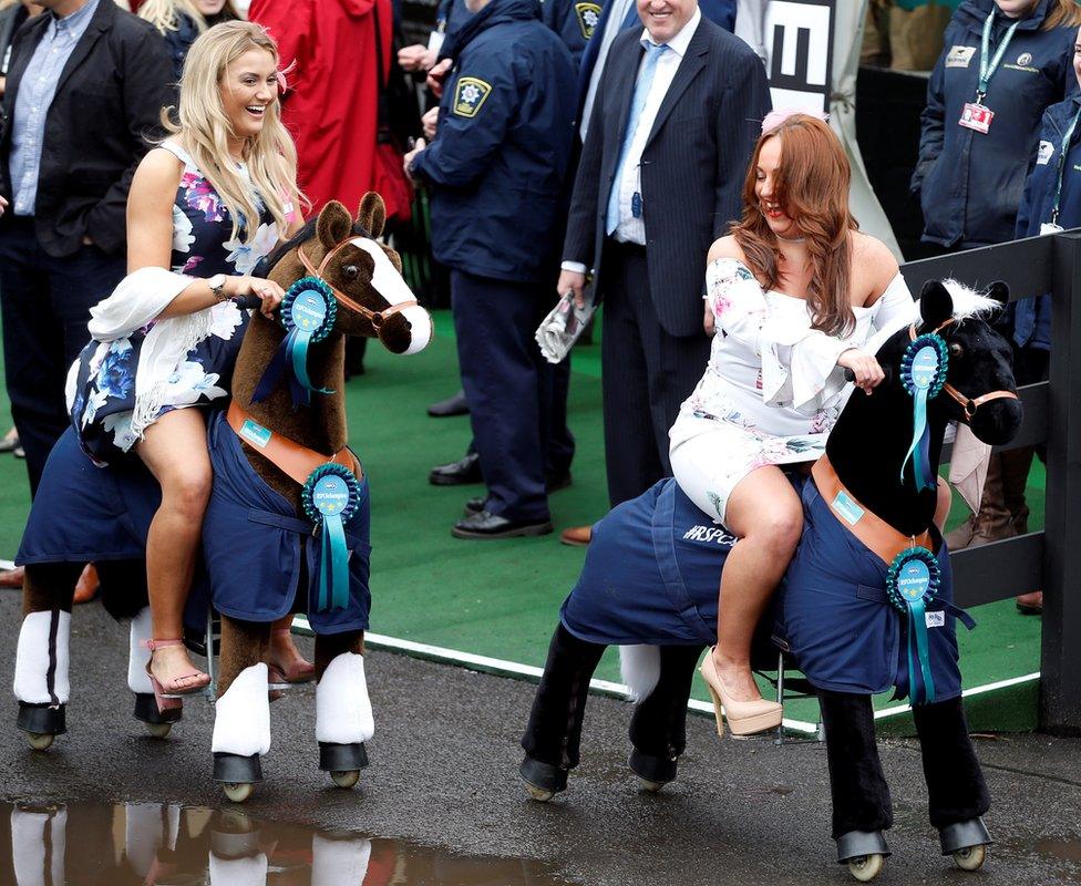 Two ladies riding on toy horses