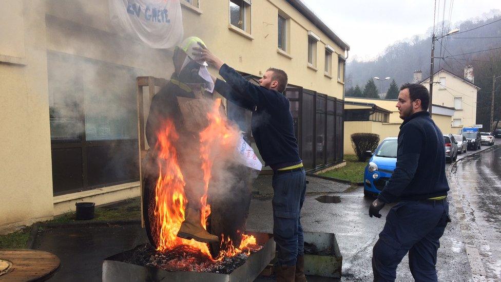 Two men stoke a fire they keep lit as part of their protest