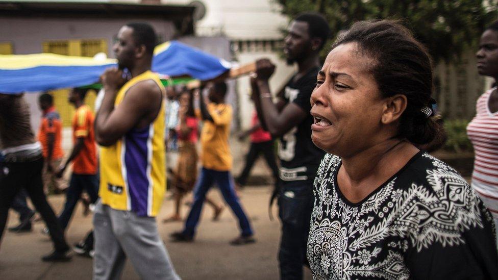 Protesters carry the body of Axel Messa, 30, wrapped in the flag of Gabon, in a street of the Libreville district of Nzeng Ayong, 2 September 2016