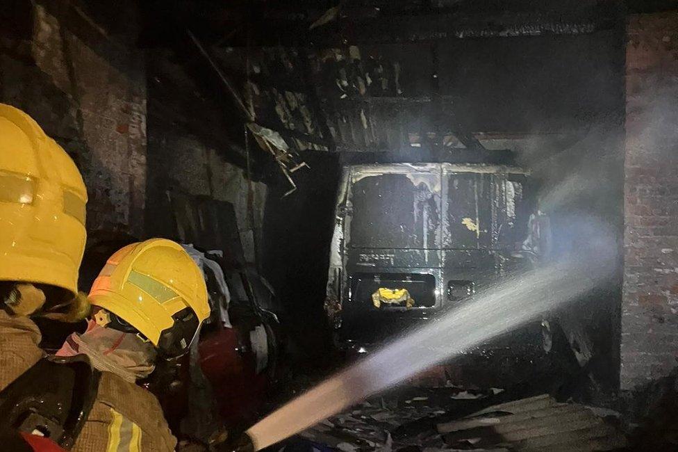 Firefighters with a hose damping down a van