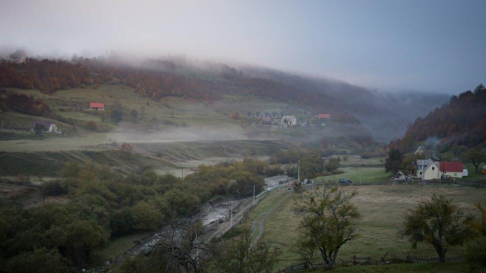 Misty valley landscape with a few houses