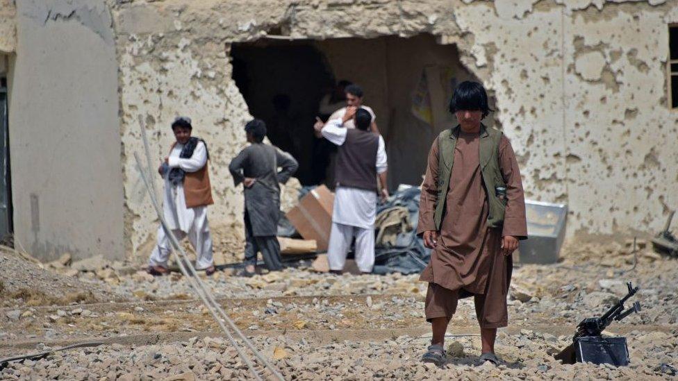 Afghan security forces guard a damaged building