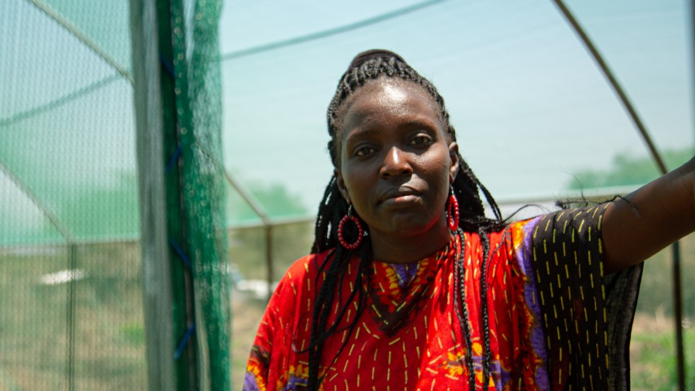 Women stands in greenhouse with her arm resting