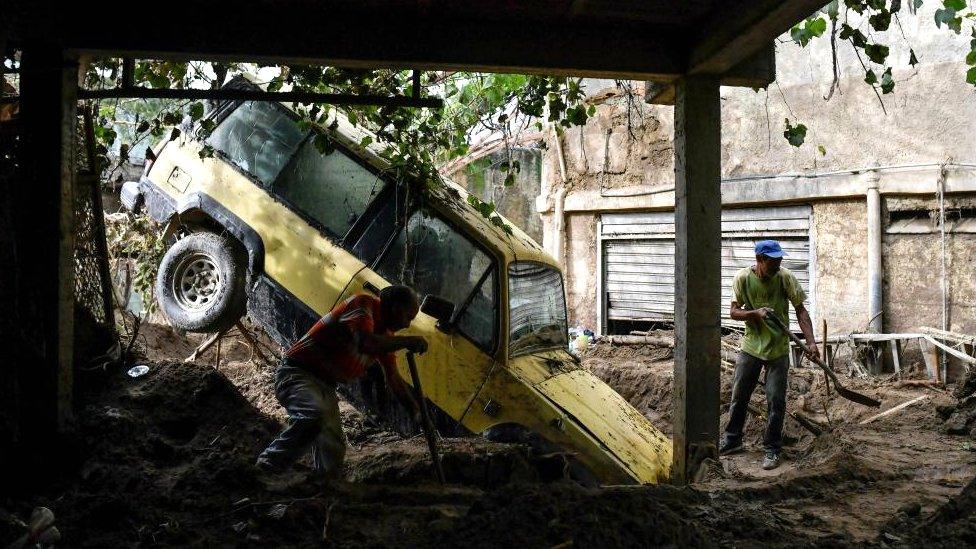 Residents remove mud inside a house after devastating floods swept through the town over the weekend, in Las Tejerias, Venezuela October 11, 2022