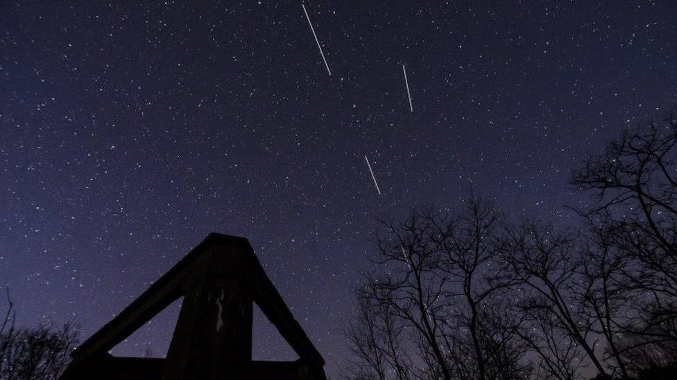 A computer-generated image from several long-exposure images shows Starlink satellites in the sky above the concrete base of a former heating plant in Salgotarjan, Hungary, 20 April 2020.