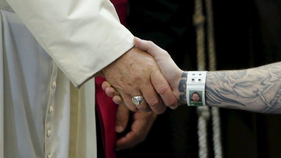 Pope Francis shakes hands with a US prisoner