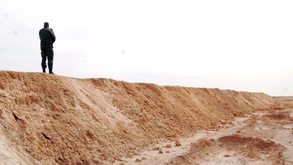 A Tunisian soldier stands on a sandbank during a presentation of the anti-jihadi fence, in near Ben Guerdane, eastern Tunisia, close to the border with Libya