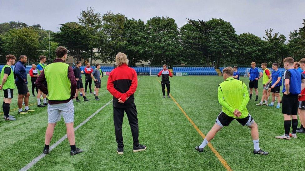 Players and coaches on a football pitch