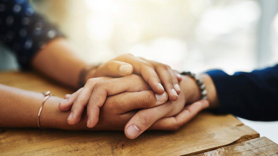 Two pairs of hands holding each other