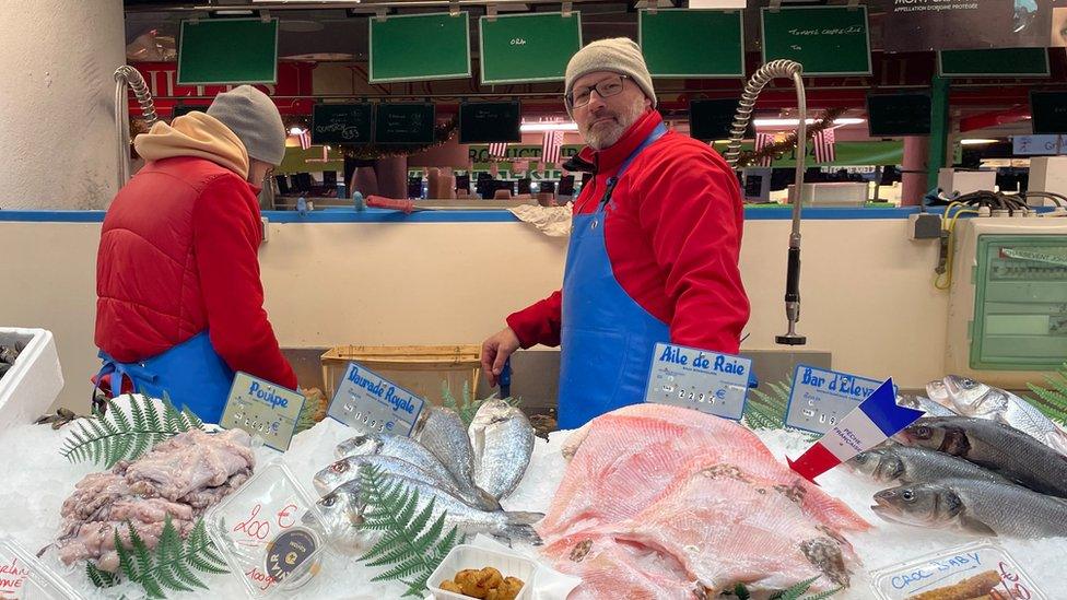 Johan Chassevent stands next to a colleague behind a table with fish