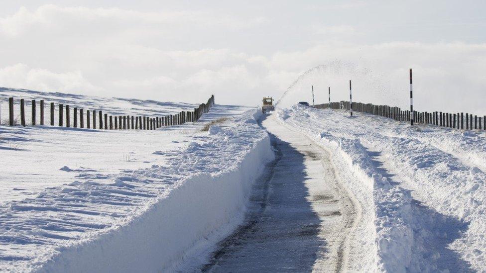 A snow blower clearing snow from a rural route