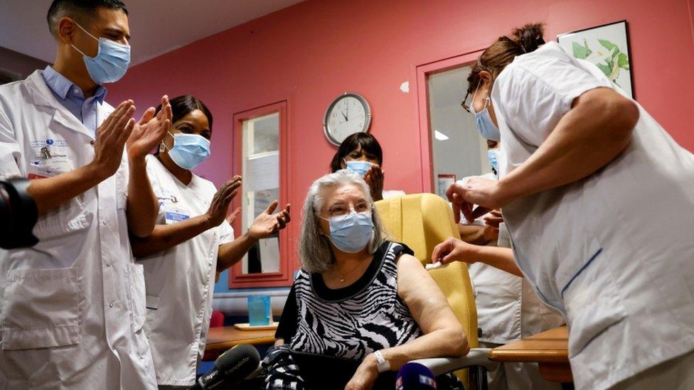 Healthcare workers applaud Mauricette, 78, after she received the first dose of the Pfizer-BioNTech vaccine in the country