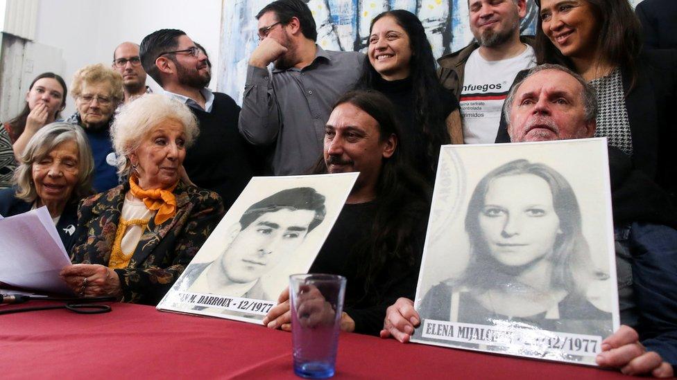 Mr Darroux, his uncle Roberto and Estela de Carlotto, president of Grandmothers of Plaza de Mayo, hold up photos of Mr Darroux's parents