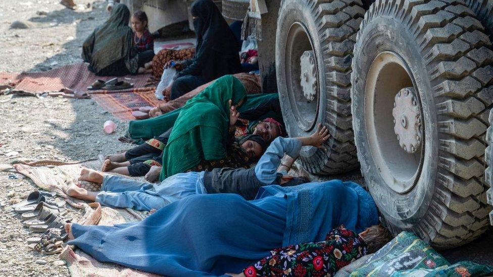 Afghan refugees resting beside a truck