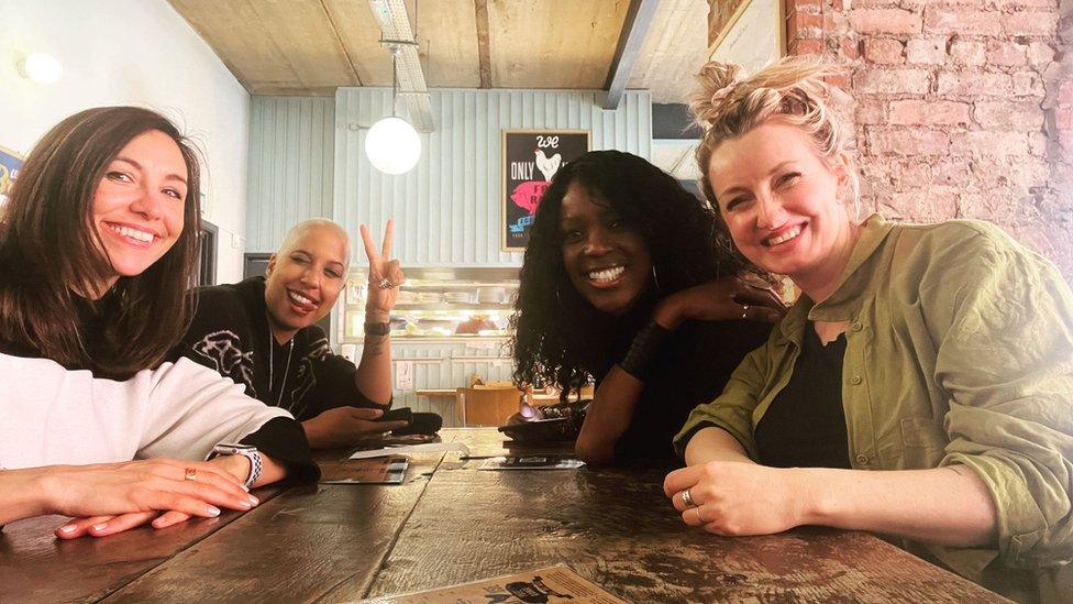 Four women around a table pose for the camera