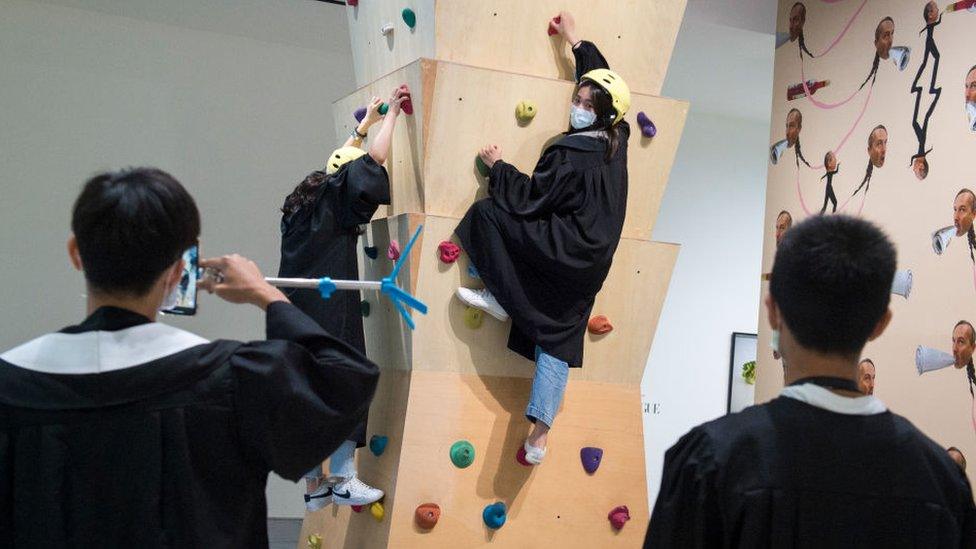 Woman climbing wall wearing a mask