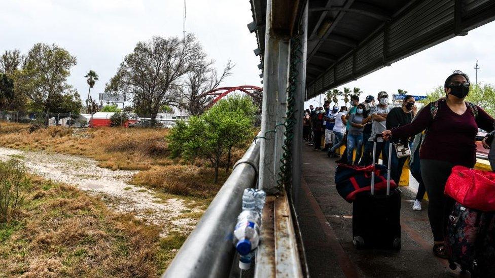 Migrants mostly form Central America wait in line to cross the border at the Gateway International Bridge into the US from Matamoros, Mexico to Brownsville, Texas, on March 15, 2021.