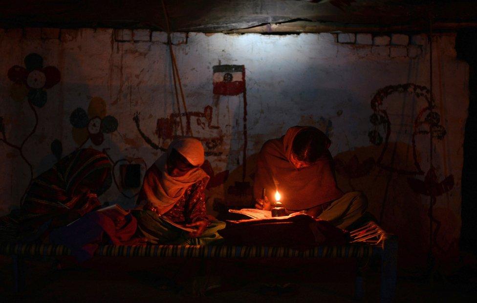 Two Indian girls study by candlelight