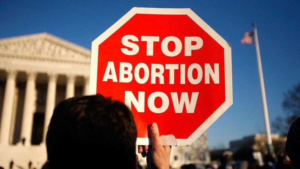 An anti-abortion campaigner holding up a sign reading 'stop abortion now', outside the US Supreme Court