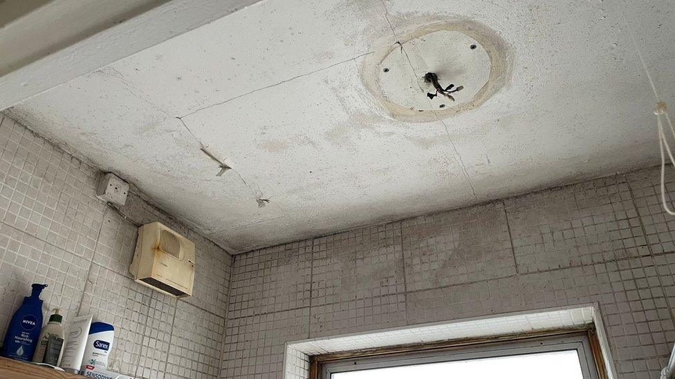 Live wires hang from a bathroom ceiling