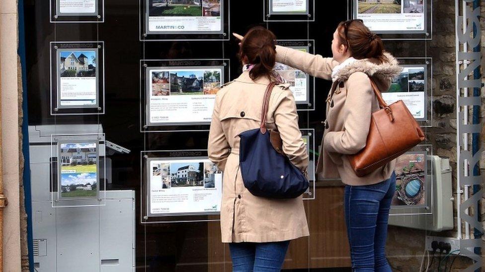 Women look in estate agent window