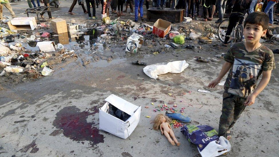 A boy walks past the scene of a twin suicide bomb attack in Sadr City, Baghdad (28 February 2016)