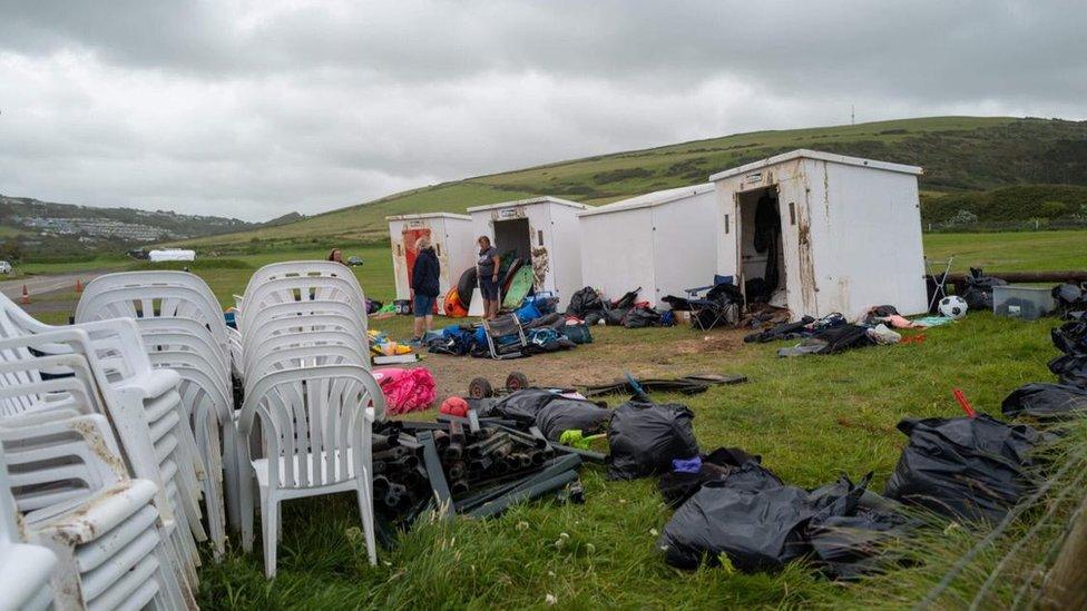 People pulling their belongings out of washed up huts