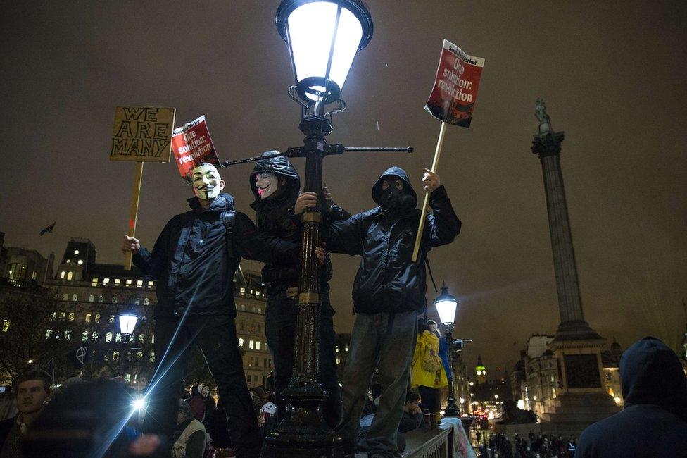 Three men hold onto a light post and signs