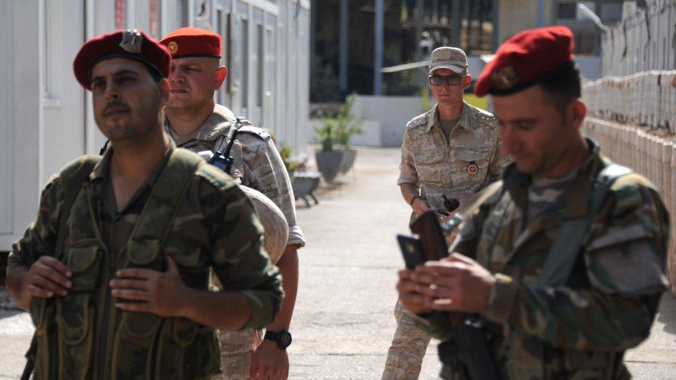 Russian soldiers, standing behind these two Syrian soldiers are part of the Russian force at the naval base at Tartus