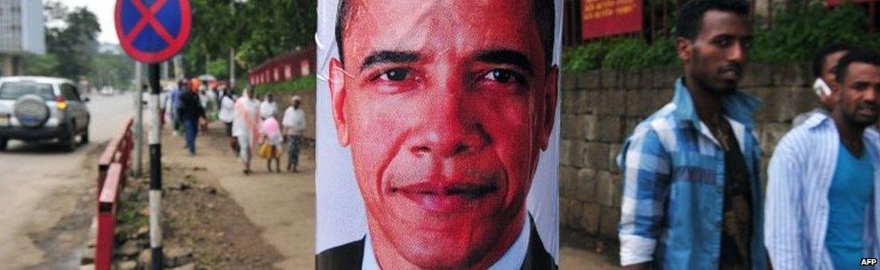 Pedestrians walk past a poster of US President Barack Obama before his arrival in Addis Ababa on 26 July 2015