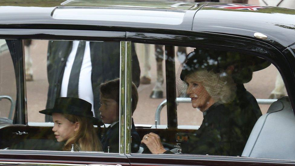 Princess Charlotte, Prince George and the Queen Consort Camilla sit in a car following the funeral procession.