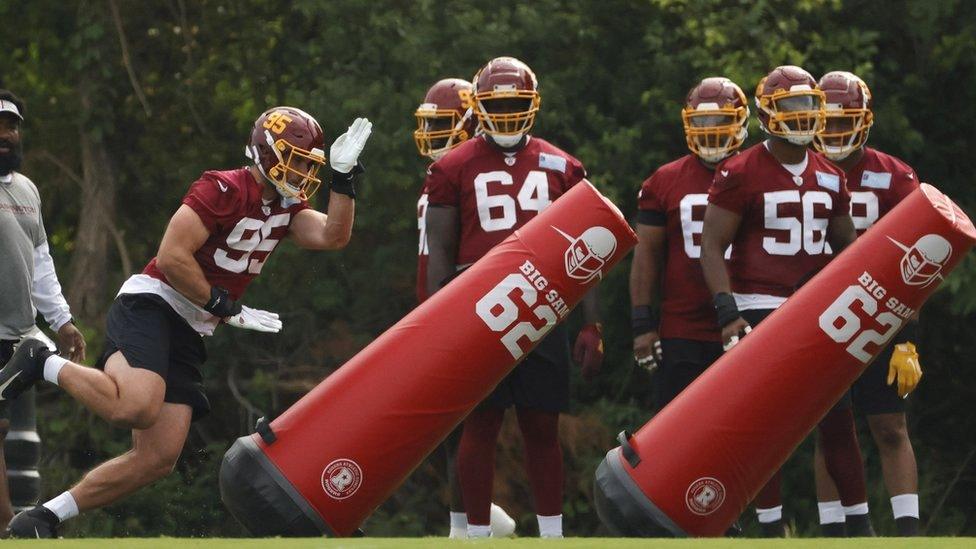 Washington Football Team defensive end Casey Toohill (L) runs around blocking dummies during drills