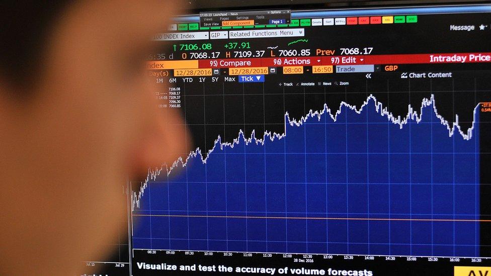 A person looking at a rising FTSE graphic