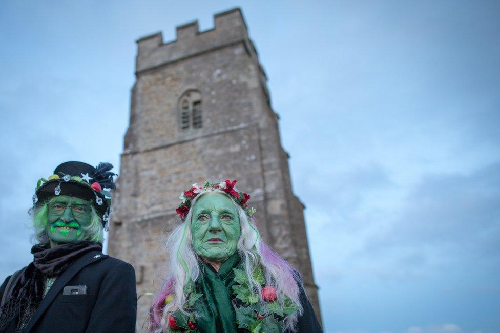 People watching the sun rise on Glastonbury Tor